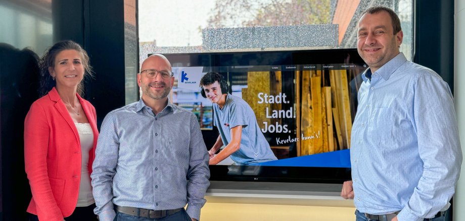 Collaborateurs de la ville devant une vitrine avec des prospectus et un écran