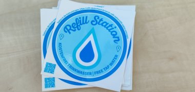 Die blau-weißen Aufkleber der Refill Deutschland-Initiative zeigen an, dass hier kostenfrei Trinkwasser erhältlich ist. 